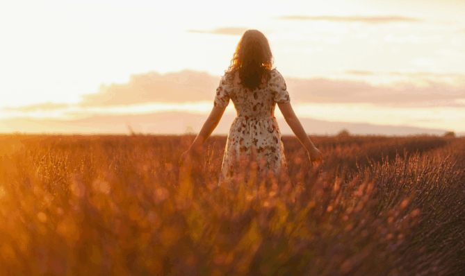 Kobieta w letniej sukience w polu lawendy o zachodzie słońca, symbolizująca letnie przesilenie i duchową transformacja z marką Creatoz.