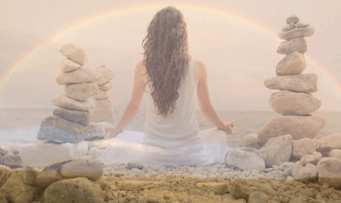 Kobieta medytująca w otoczeniu kamieni i tęczy, symbolizująca duchowe oczyszczenie i uwolnienie emocji