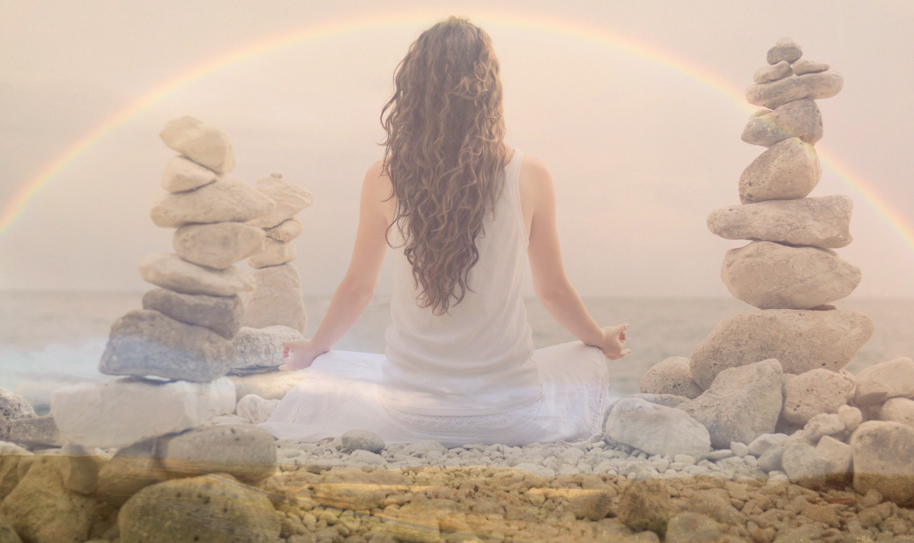 Kobieta medytująca w otoczeniu kamieni i tęczy, symbolizująca duchowe oczyszczenie i uwolnienie emocji