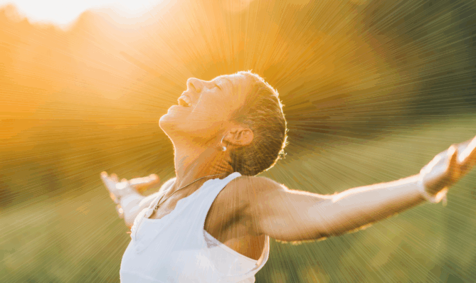 Kobieta w promieniach słońca symbolizująca letnie oczyszczanie przestrzeni i wzmacnianie aury za pomocą Harmonizatora Creatoz