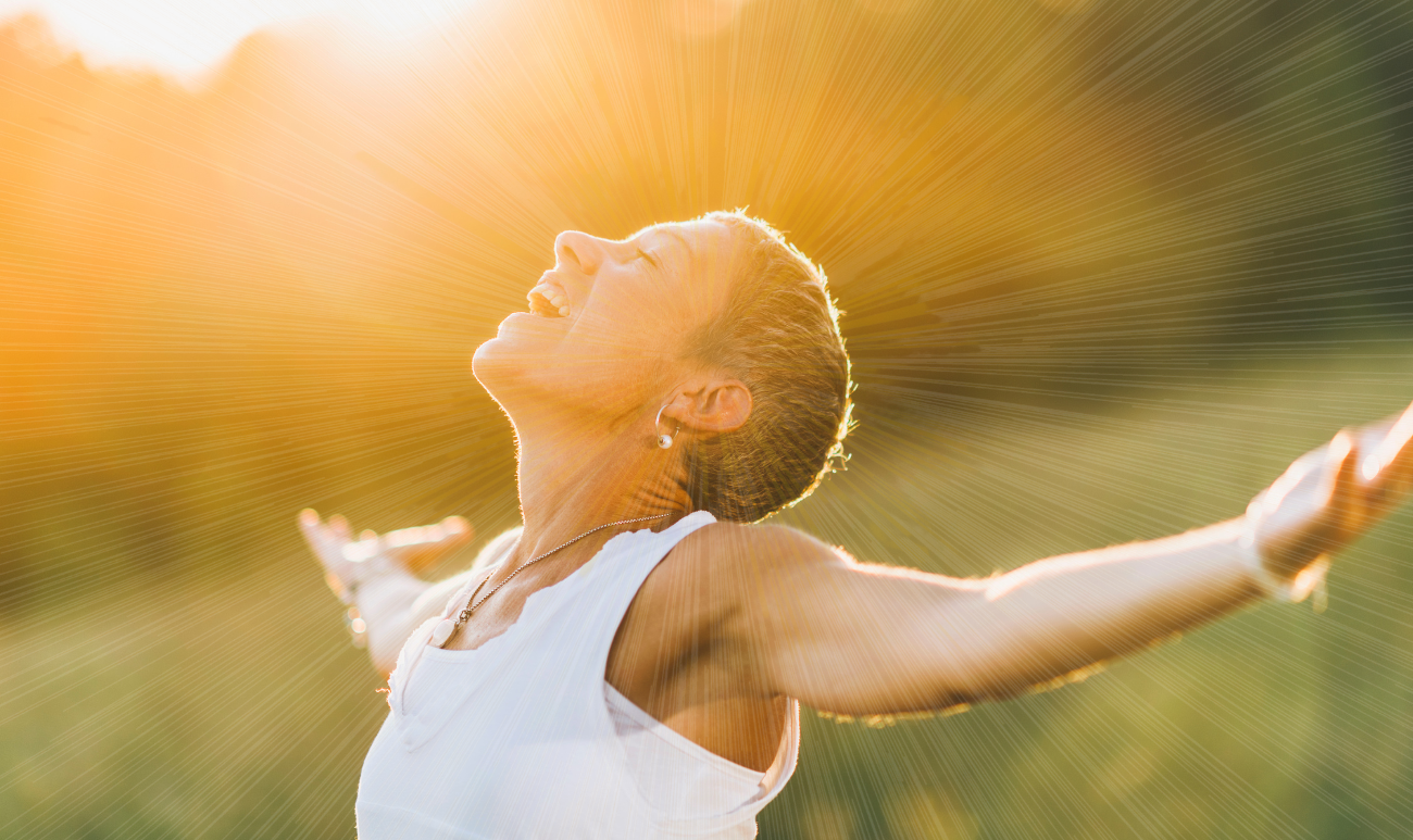 Kobieta w promieniach słońca symbolizująca letnie oczyszczanie przestrzeni i wzmacnianie aury za pomocą Harmonizatora Creatoz